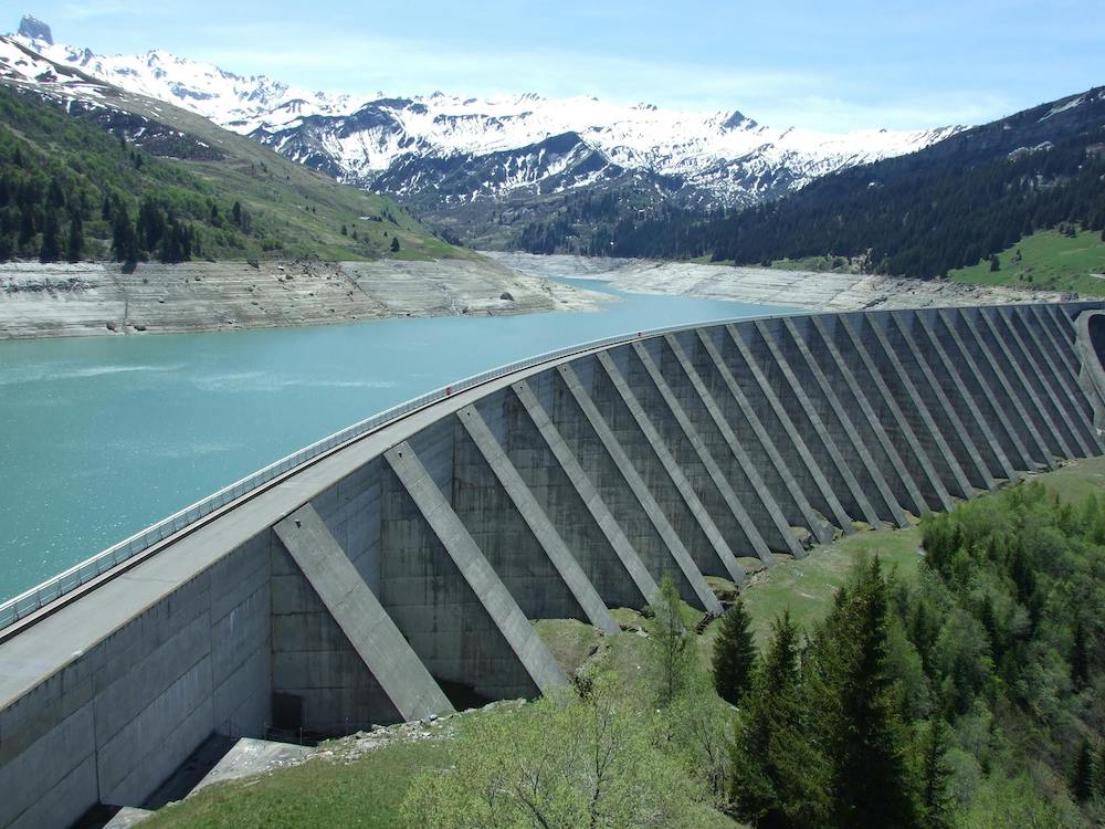 hydropower dam in front of snowy mountains