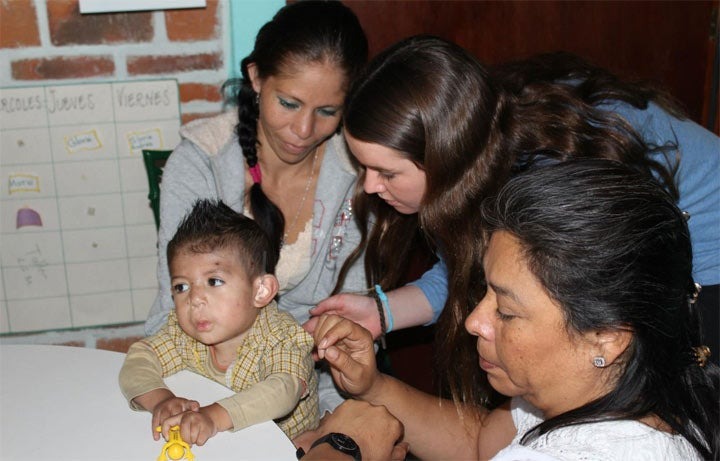 Grace O'Brian, recipient of the Gloria Barron prize, helping a child install a hearing aid