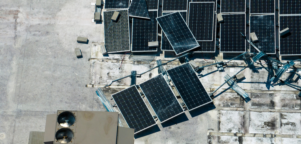 A photo showing damage to a commercial solar array on a flat roof following Hurricane Ian in 2022