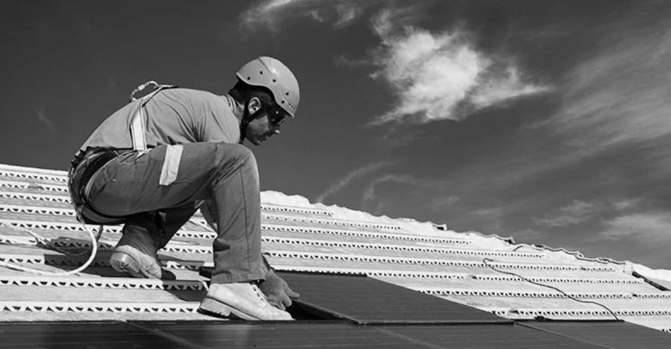 black and white photo of man installing solar on a roof