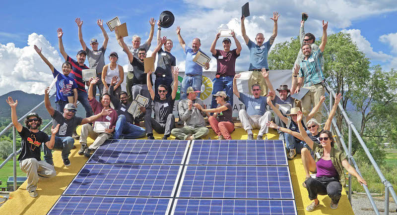 new solar industry workers celebrate around a solar panel after completing course on solar