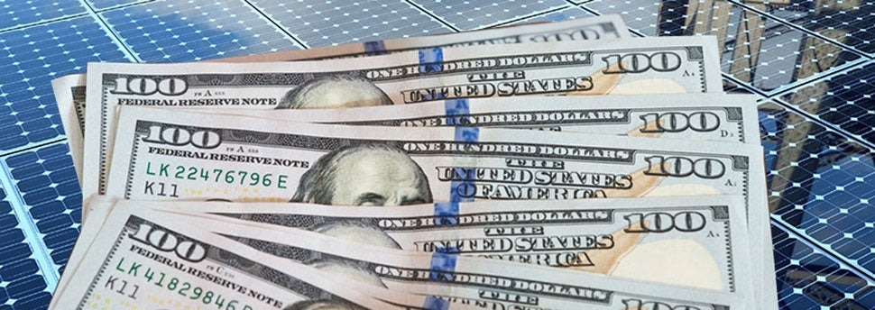 solar panels with hundred-dollar bills stacked over top