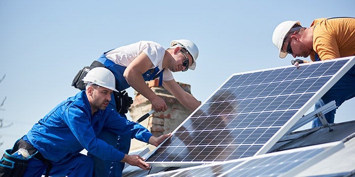 crew of male contractors installing solar panels on a roof